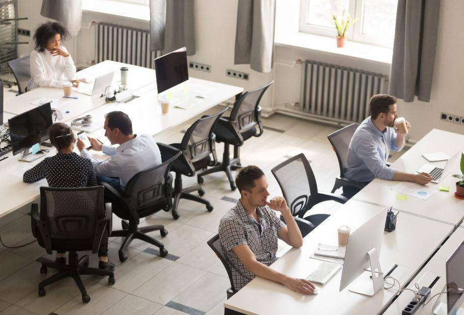 Personas trabajando en una oficina con escritorios compartidos.